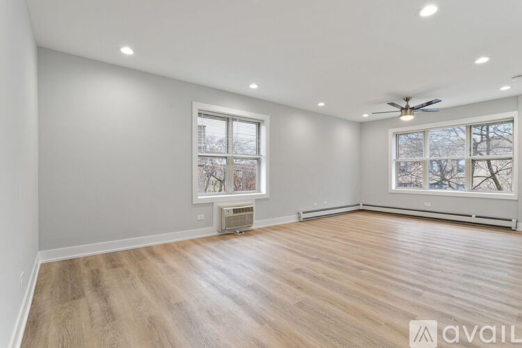 A spacious room with wooden flooring and a ceiling fan.