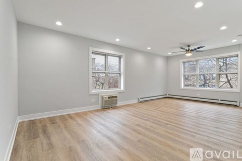 A spacious room with wooden flooring and a ceiling fan.