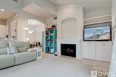 A living room with a fireplace and a television displaying a beach scene.
