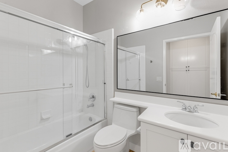 A white bathroom with a toilet, sink, and shower.