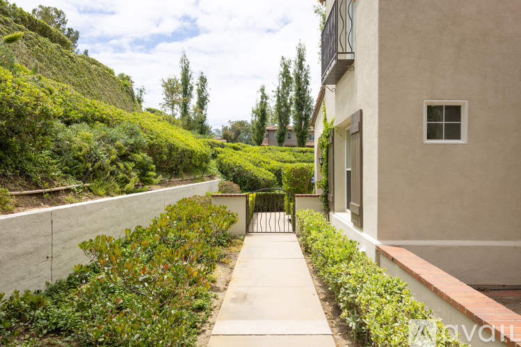 A narrow pathway leads to a building with a small window.