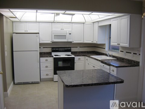 A kitchen with white cabinets and a black countertop.