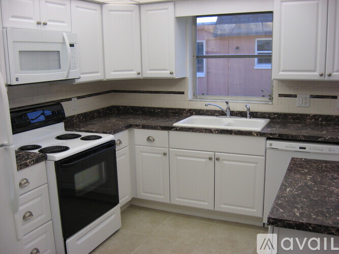 A kitchen with white cabinets and black countertops.