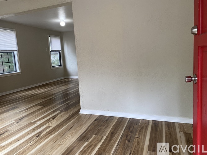 A room with wooden flooring and a red door.