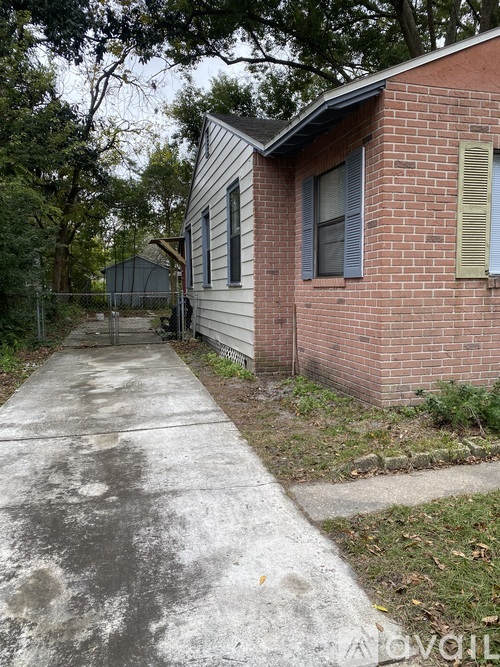 A brick house with a concrete walkway in front.