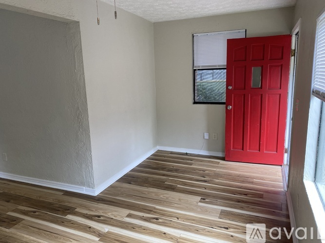 A room with a red door and wooden flooring.