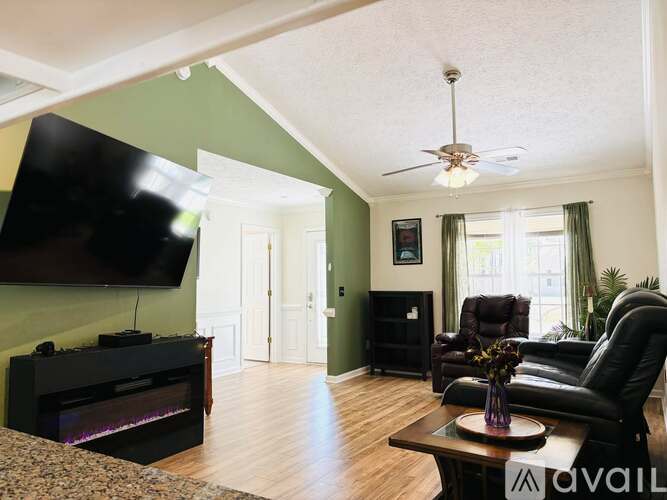 A living room with a black leather chair and a flat screen TV mounted on the wall.