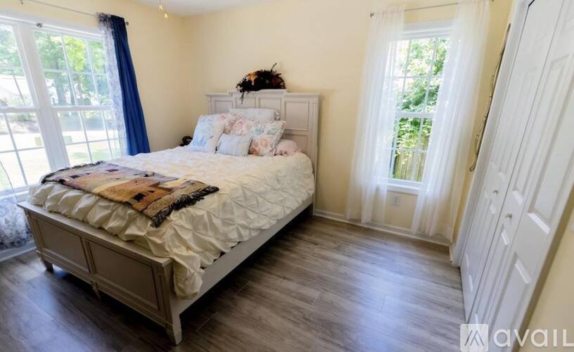 A bedroom with a large bed and a window with curtains.