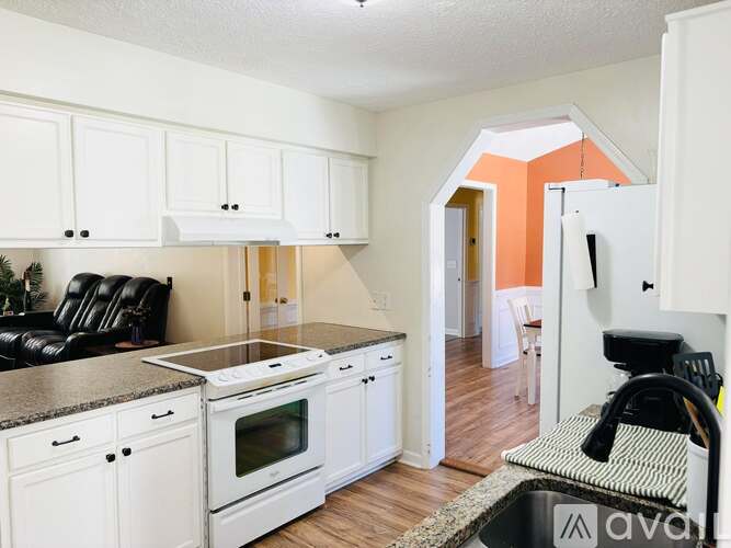 A kitchen with white cabinets and a black countertop.