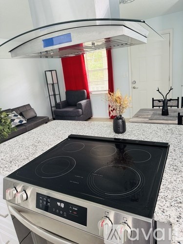 A modern kitchen with a stove top oven and a grey granite countertop.