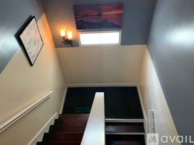 A staircase with a wooden handrail and a window with a sunset view in the background.