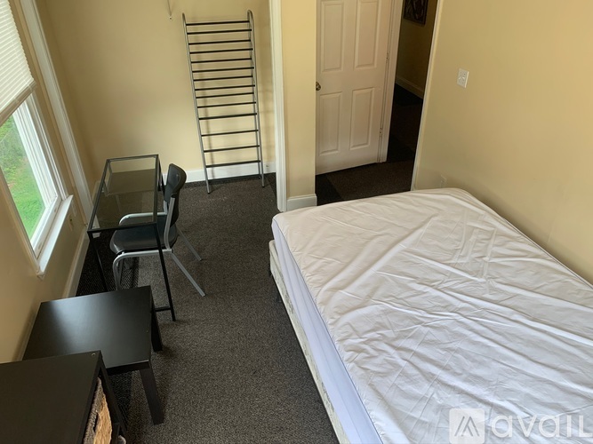 A bedroom with a bed, desk, chair, and a window.