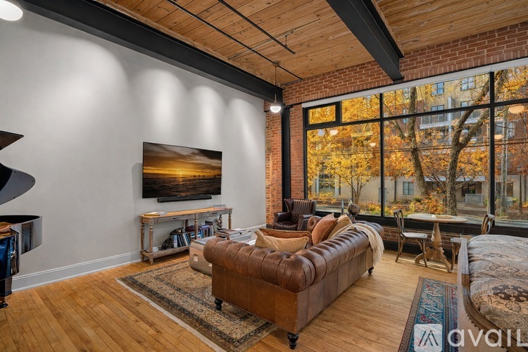 A living room with a brown leather sofa and a painting on the wall.