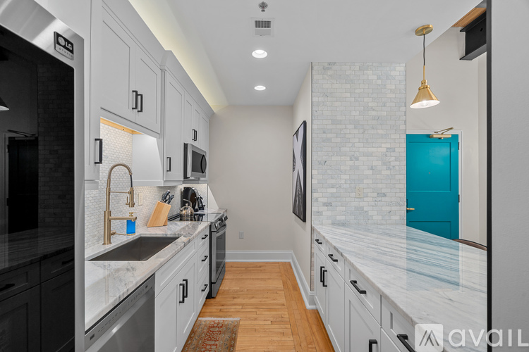 A modern kitchen with a long counter and a blue door.