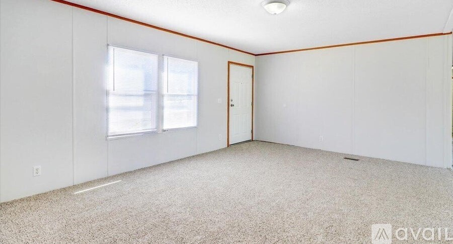 A room with a carpeted floor, a door, and a window with blinds.