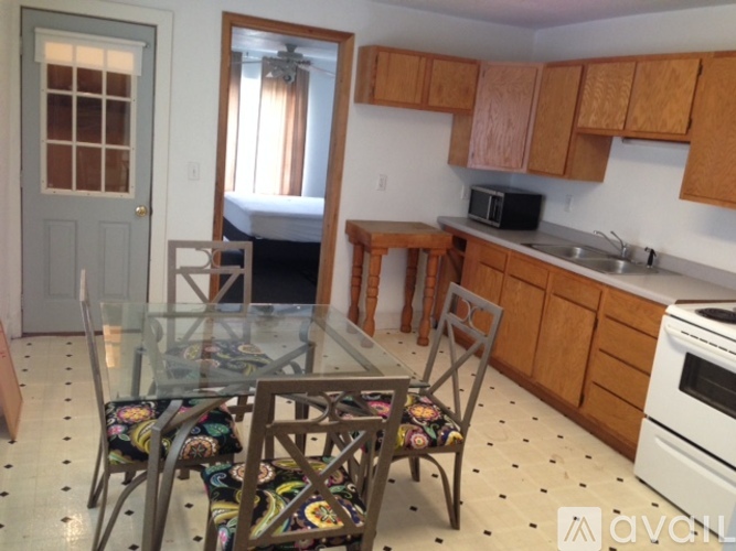 A kitchen with wooden cabinets and a glass table with chairs.