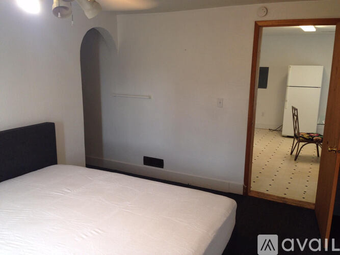 A bedroom with a white bed and a mirror on the wall.