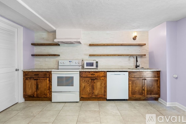 A kitchen with wooden cabinets and a white oven and dishwasher.