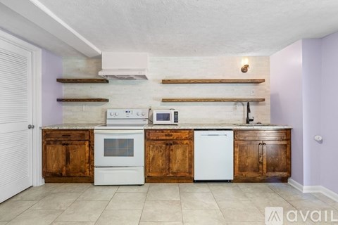 A kitchen with wooden cabinets and a white oven and dishwasher.