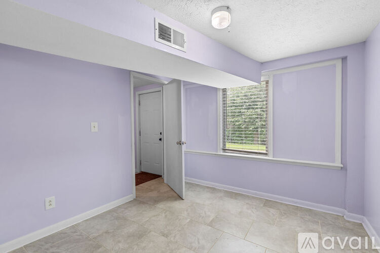 A room with purple walls and a window with blinds.
