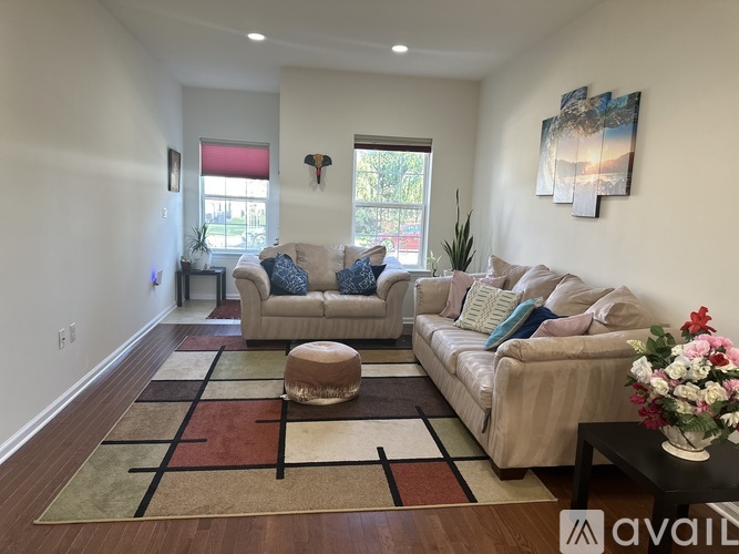 A living room with a rug, two couches, and a table with flowers.