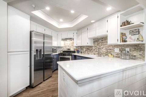 A kitchen with white cabinets and a marble backsplash.