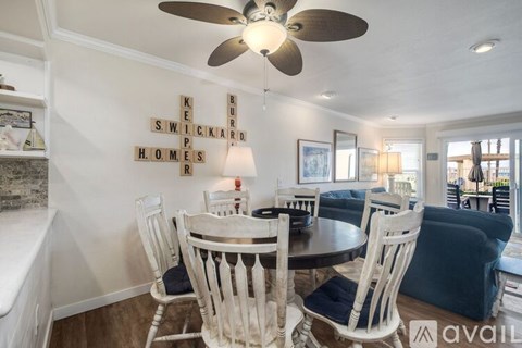 A dining room with a table and chairs and a sign on the wall.