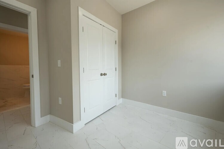 A white door is in a room with a marble floor.