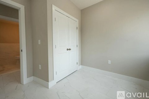 A white door is in a room with a marble floor.