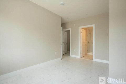 A spacious room with a marble floor and two open doors.