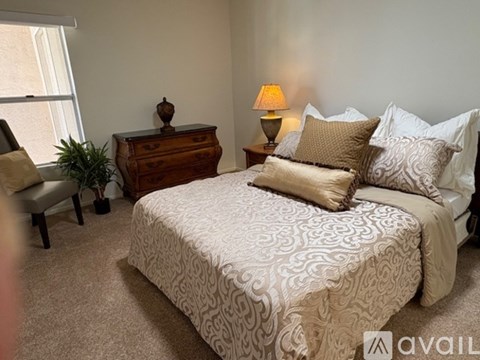 A bedroom with a bed, nightstand, and chair.