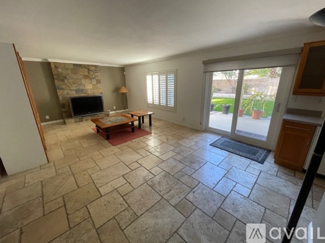 A living room with a stone floor and a stone fireplace.