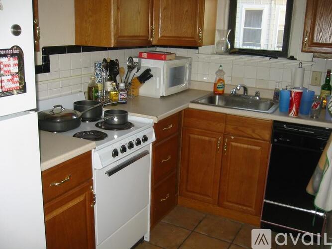 A kitchen with a white stove top oven and wooden cabinets.