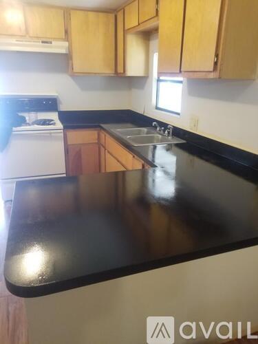 A kitchen with wooden cabinets and a black countertop.