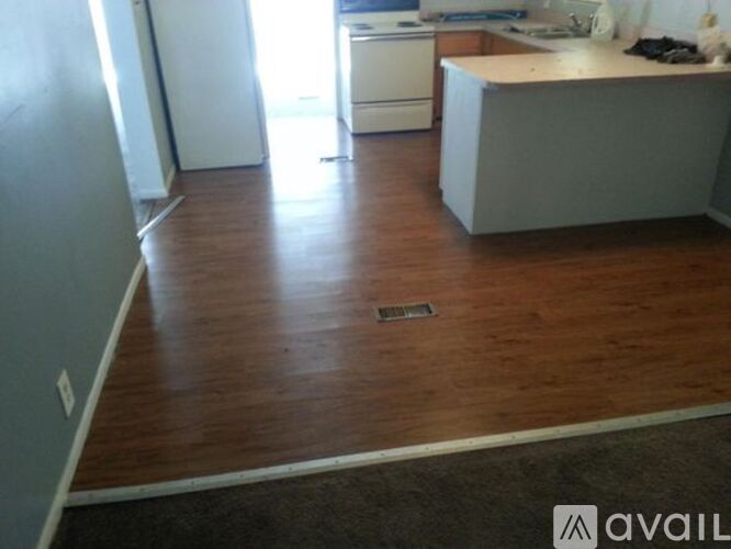 A kitchen with a white fridge and wooden floors.