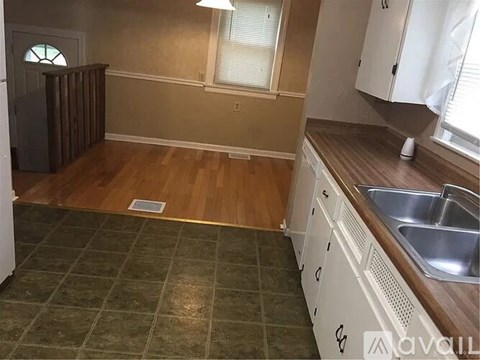A kitchen with white cabinets and a green tile floor.