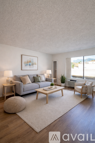 A living room with a grey couch, a wooden coffee table, and a large window.