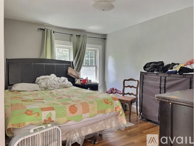 A bedroom with a bed, chair, and window.