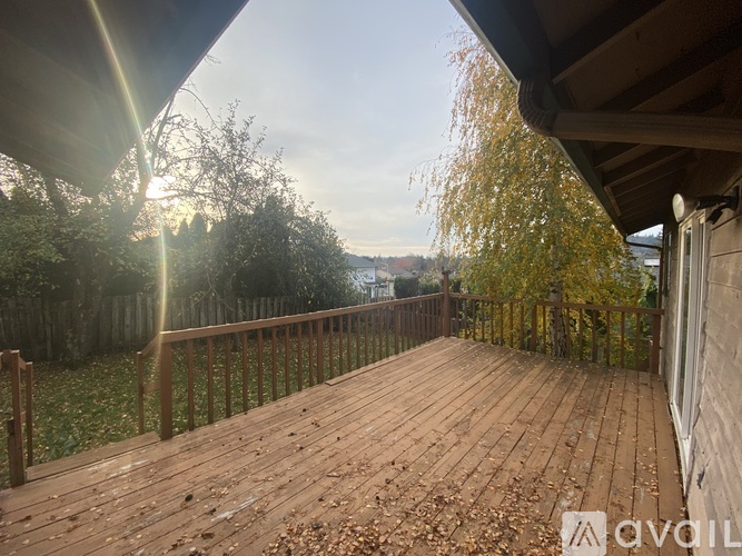 A wooden deck with a railing and trees in the background.