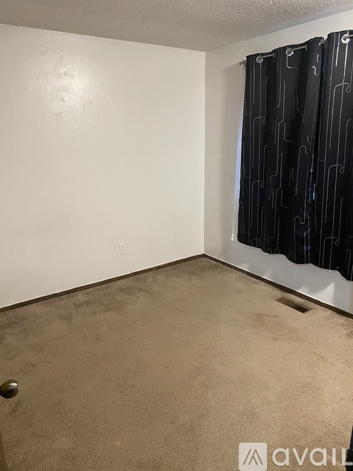 A room with a carpeted floor and a black curtain with a white pattern.