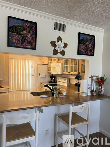 A kitchen with a counter and two chairs.