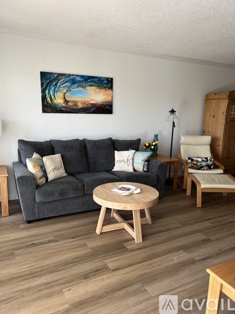 A living room with a grey couch, a wooden coffee table, and a painting on the wall.
