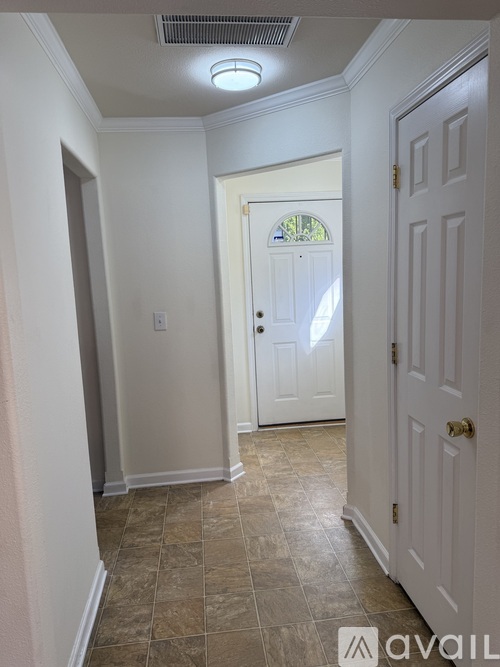 A hallway with a tiled floor and white walls.
