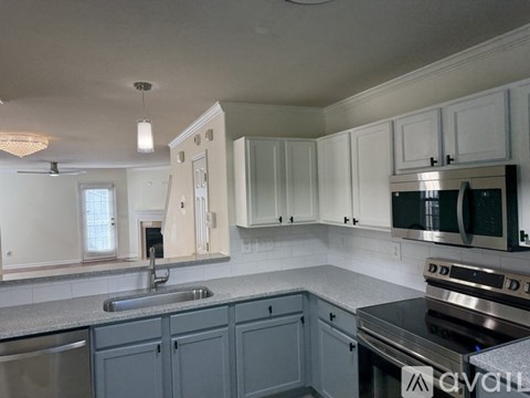 A kitchen with white cabinets and a stainless steel sink.