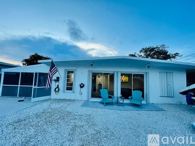 A house with a flag and two chairs outside.