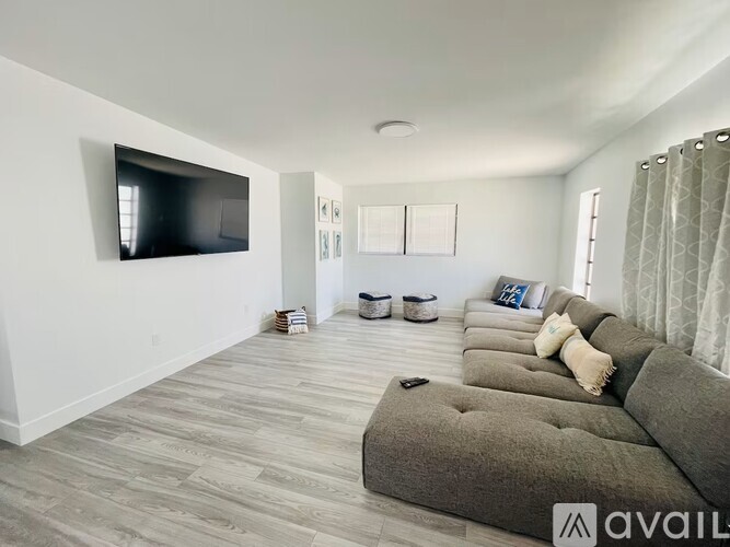 A living room with a grey couch and a flat screen TV mounted on the wall.