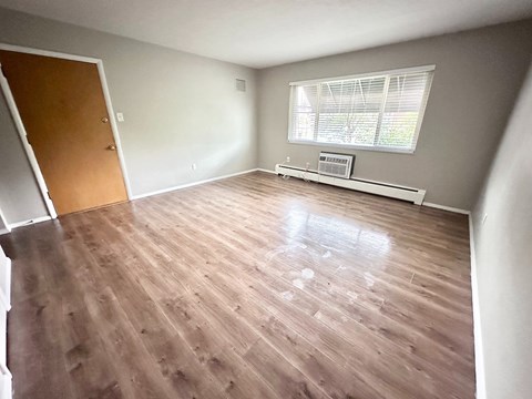 A room with wooden flooring and a window with blinds.