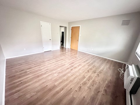 A room with wooden flooring and white walls.
