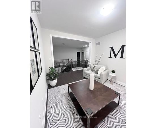 A living room with a coffee table and a large letter M on the wall.