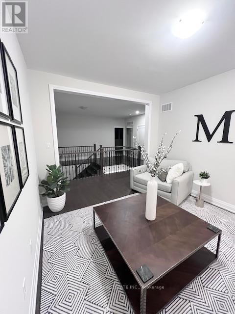 A living room with a coffee table and a large letter M on the wall.